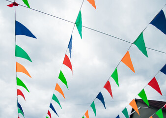 Small, multicolored flags on a blue sky background. Colorful background. Carnival festival, decoration of a park or a street festival.