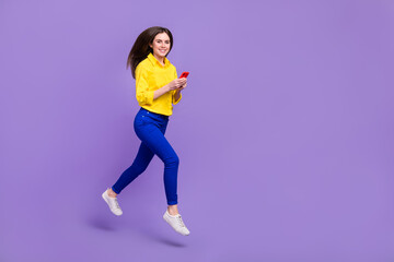 Fototapeta na wymiar Full length body size view of beautiful trendy girl jumping using device blog app isolated over bright violet purple color background