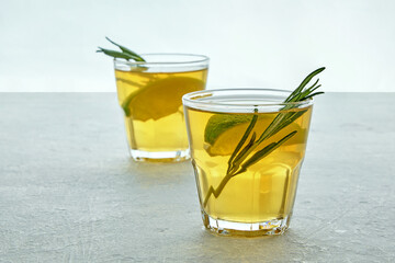 Two glass cup of homemade fermented kombucha tea with rosemary and lemon lime on a light gray...