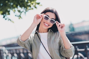 Photo of positive funny girlfriend wear green outfit arms dark eyewear enjoying sunny weather walking outdoors city street