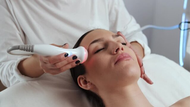 Video of cosmetologist making ultrasonic cleaning and rejuvenation the face to beautiful woman on the spa center.