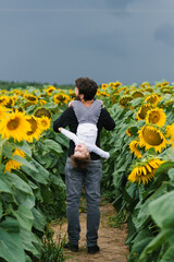 Father with a young son on his shoulders walking and having fun in a field of sunflowers.