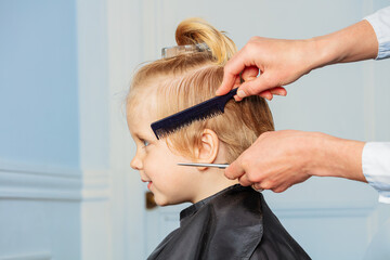 Fototapeta premium Profile of a little boy smiling while hairdresser do haircut