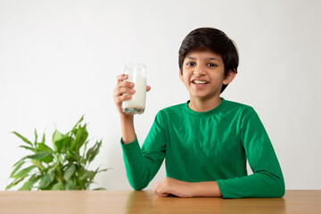 Portrait of smiling boy drinking milk during breakfast - Powered by Adobe