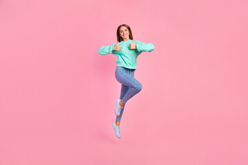 Full size photo of energetic excited girl jumping hands fingers demonstrate thumb up isolated on pink color background