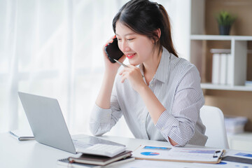 Young asian businesswoman beautiful charming smiling and talking on the mobile phone in the office