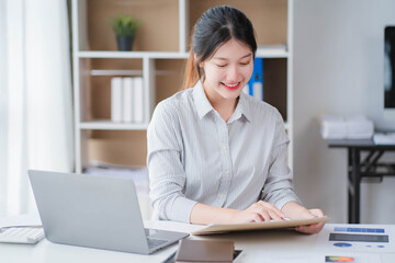 Young asian businesswoman beautiful charming smiling and talking on the mobile phone in the office