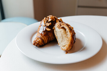 appetizing croissant with chocolate and peanuts on a plate