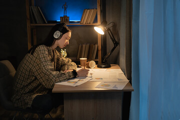 asian female freelancer working at night analyzing information in documents while sitting at table with graphics in cozy contemporary apartment, girl student work with new project