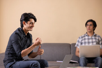 Fototapeta premium Two happy teenage boys doing homework at home using laptop