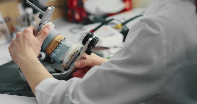 Dental technician makes a plaster cast of jaw models in an articulator. Production of a dental implant in a dental laboratory