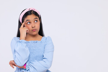 Portrait of thoughtful girl with hand on head standing against plain background