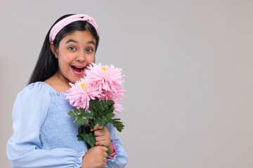 Portrait of excited girl holding a bouquet of flowers against plain background