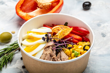 Tuna salad with tomatoes, corn olives, eggs and microgreen in paper bowl package for take away or food delivery, package for take away