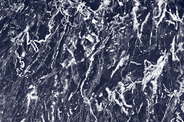 Transparent dark blue ice of frozen Baikal lake with white cracks pattern. Beautiful winter nature background.