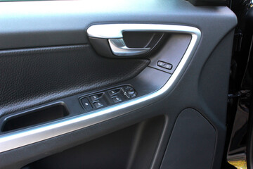 Door handle with windows controls and adjustments in black leather interior. Window switches.