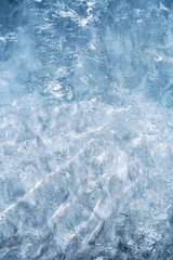 Obraz na płótnie Canvas Transparent blue ice of frozen Baikal lake with waves pattern. Beautiful winter nature background.