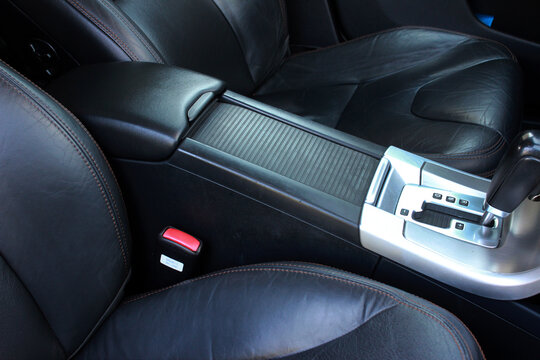 Automatic transmission lever shift. Gear shifter and car dashboard. Drivers armrest. Black leather car interior.
