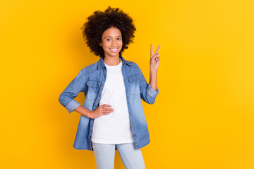 Portrait of attractive cheerful wavy-haired teen age girl showing v-sign isolated over bright yellow color background