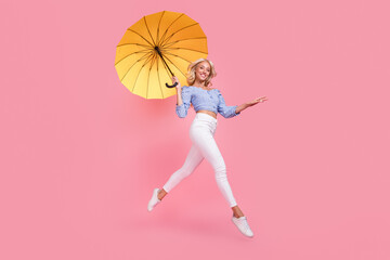 Full length photo of charming shiny lady wear off shoulders top jumping flying umbrella walking isolated pink color background © deagreez