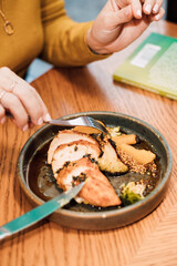 Women's hands with a fork and knife over a plate of food