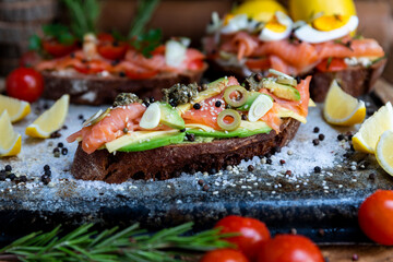 Salted salmon open sandwich with guacamole, avocado, olives, cheese, pesto and garlick. Healthy seafood
