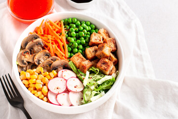 Vegan buddha bowl with tofu, colorful vegetables on base of brown rice.