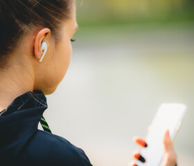 Young caucasian girl with wireless headphones in the park using tablet and smiling