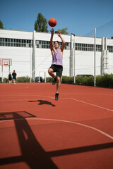 young guy plays basketball on the basketball court. throws the ball into the ring. doing sports. healthy body and healthy lifestyle