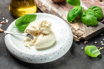 Burrata cheese with Basil leaves on white plate on dark background. banner, menu, recipe place for text, top view