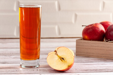 Red raw apples in box with glass of apple juce in front of wall. Simple composition. Selective focus.