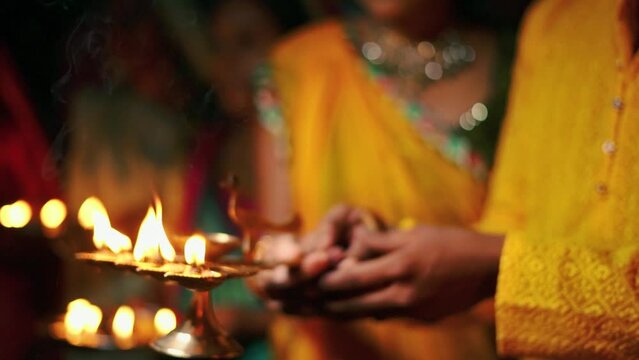 aarti lamp, close up of brass oil lamp lit on hand of indian couple doing aarti, hindu ritual of worshiping god, Indian festivals
