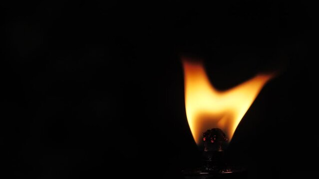 Fire flame from a torch on a black background. The flame of fire dances in the darkness. Soft cinematic picture. Soft selective focus.