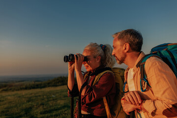 Middle age couple hiking and using binoculars