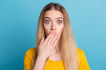 Photo portrait of scared woman covering mouth with two hands isolated on pastel blue colored...