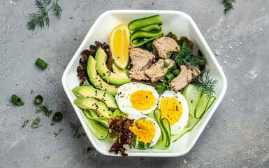 Healthy Food Bowl with Tuna Fish, avocado, egg, cucumber and fresh salad. vegetarian buddha bowl on a gray background. top view