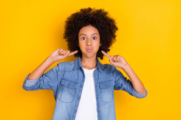 Portrait of attractive funny teen-aged girl blowing cheeks touching isolated over bright yellow...