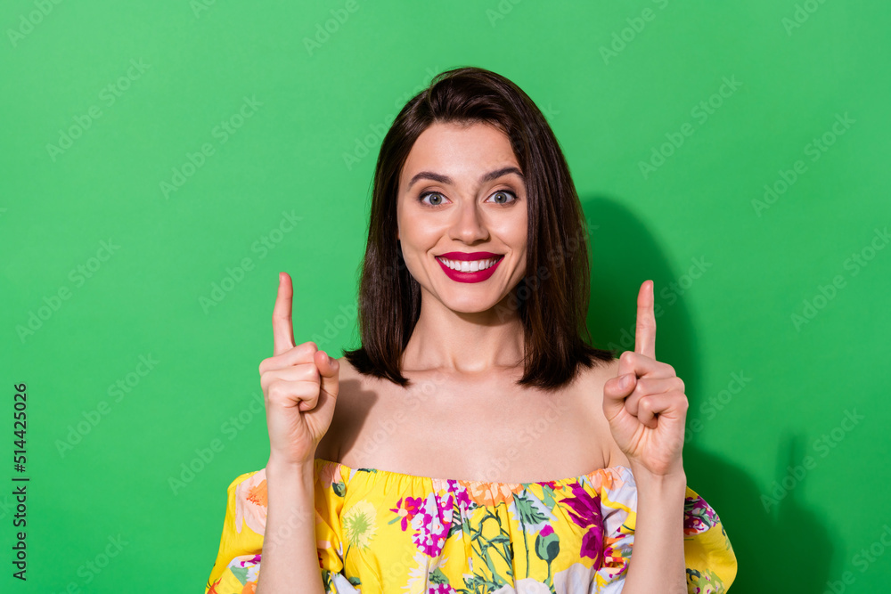 Wall mural photo of cheerful lovely lady toothy smile direct fingers up empty space isolated on green color bac