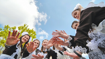 Happy Russian school graduates are stretching their hands on their last school day.
