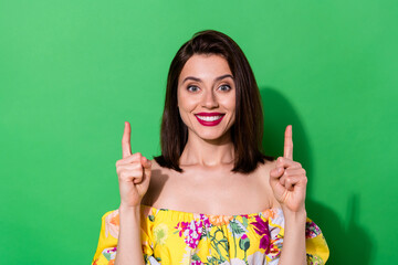 Photo of cheerful lovely lady toothy smile direct fingers up empty space isolated on green color background