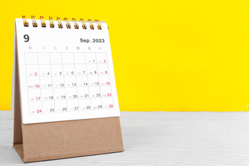 September calendar 2023 on wooden table on yellow background