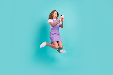 Full body photo of cute excited girl jumping hold telephone make selfie isolated on teal color background