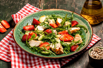 Chicken salad with arugula avocado and strawberries. Plate with a keto diet food. Top view