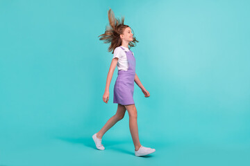 Full size profile portrait of positive lovely girl walking look empty space isolated on turquoise color background © deagreez