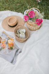 Obraz na płótnie Canvas Summer picnic. White blanket, glasses with lemonade, flowers, hat.