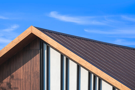 Wooden gable roof with battens decoration of vintage house against cloud on blue sky background