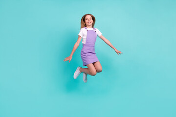 Fototapeta na wymiar Full size photo of overjoyed satisfied little girl jumping flying have fun good mood isolated on teal color background
