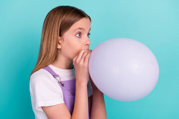 Profile photo of lovely nice small girl blowing inflate balloon look empty space isolated on teal color background