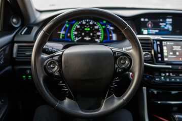 Black luxury modern car interior. Steering wheel, speedometer, display, and multimedia dashboard....