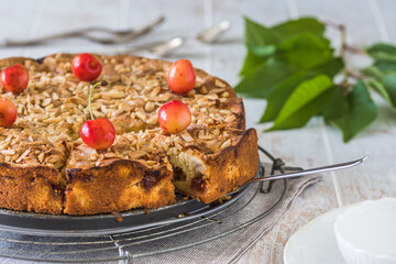 Sweet cherry pie with roasted almonds, on a white wooden table